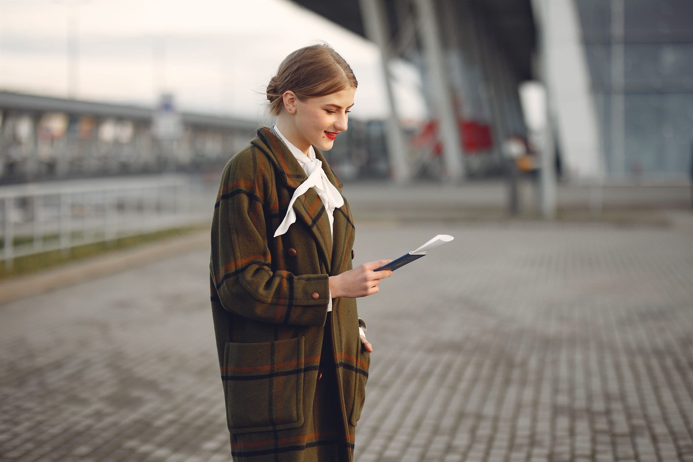 A traveller checking her phone outside an airport terminal