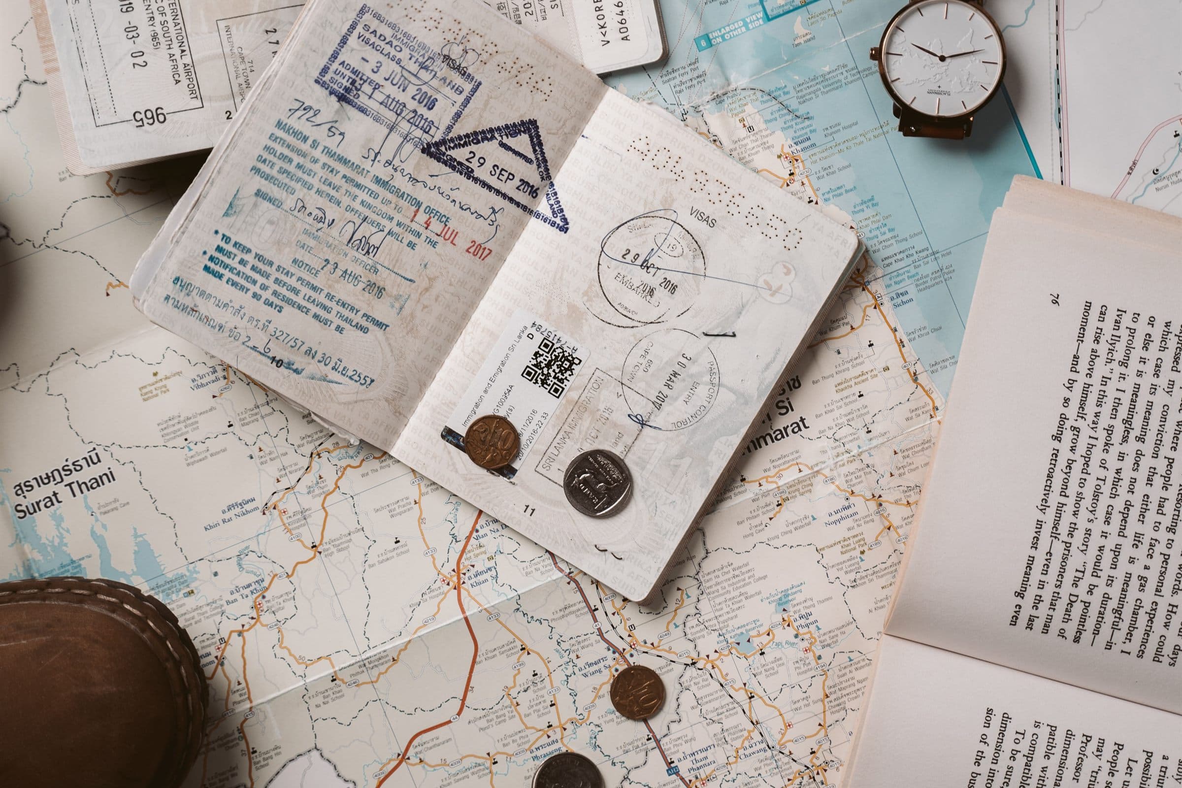 Stamped passports, a watch and coins on a travel map